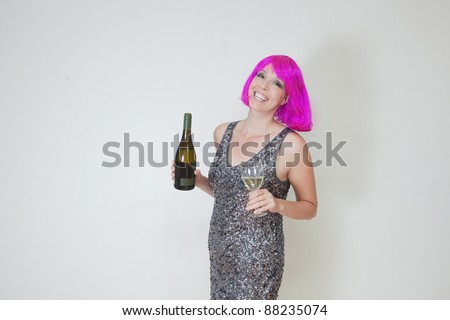 Woman ready to party in pink wig with glass of wine along with wine bottle.