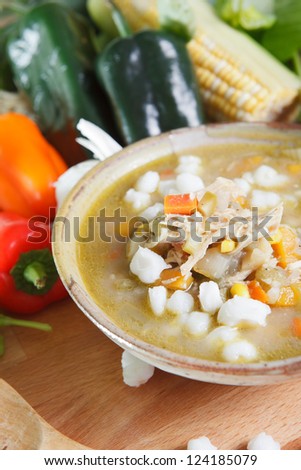 Single bowl or serving of southwestern style chicken posole garnished with carrots, peppers, garlic, and hominy.