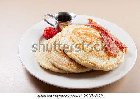 Stack of fluffy made-from-scratch pancakes with bacon and strawberry