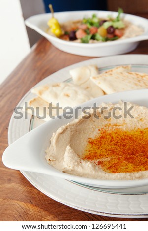 Bowl of hummus with olive oil and paprika. Served with pita bread, and ethnic Egyptian Food in the background