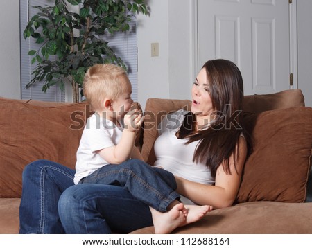 Young mother and her toddler face each other and play silly faces games, interacting with each other.