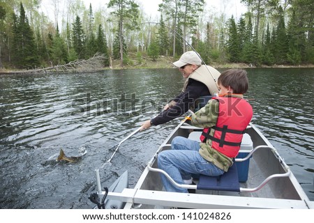 A young fisherman in a canoe catches a walleye