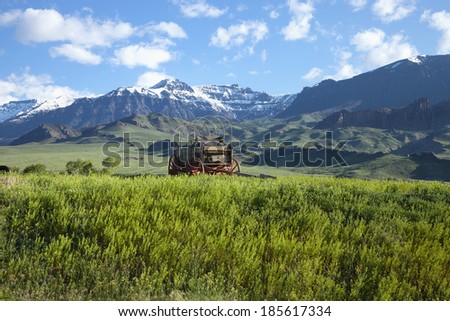 An old covered wagon sits in front of the Absaroka Mountains of Wyoming