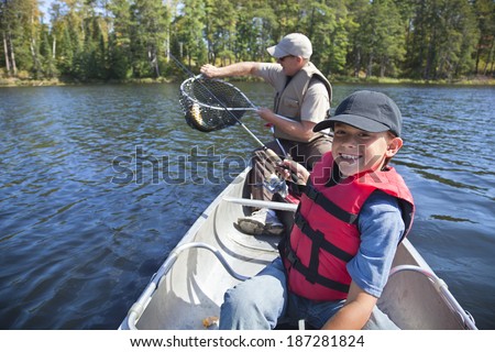 Young boy fisherman smiles while his dad takes the fish out of the net