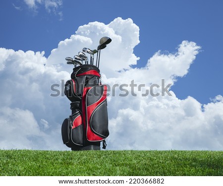 Golf clubs on grass against a blue sky and clouds