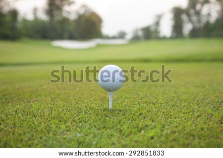 Low angle view of a white golf ball on a tee with defocused background