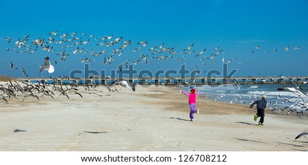 Two children running along the beach scaring birds.  Sebastian Inlet State Park, Florida