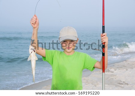 Happy kid with a fishing rod and fish  Gulf Kingfish.Background of the Gulf of Mexico. Focus on the child\'s face