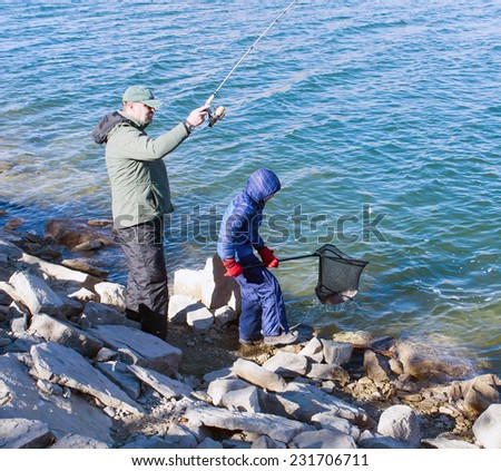 Father and son catch trout in the lake. Adult fish caught, and the child helped pull her out of a net water