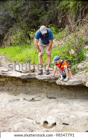 Father and son looking at fossilized dinosaur footprints. Dinosaur Valley State Park, Glen Rose, Texas