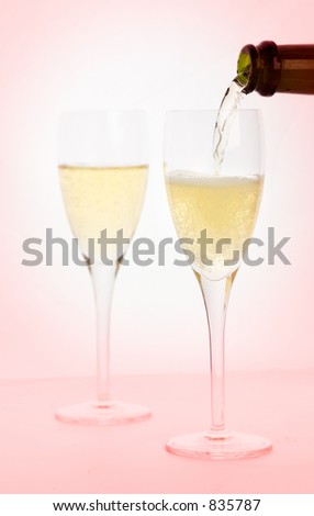 Champagne, one glass being poured, on pink.  Shallow DOF, focus on right champagne glass bubbles