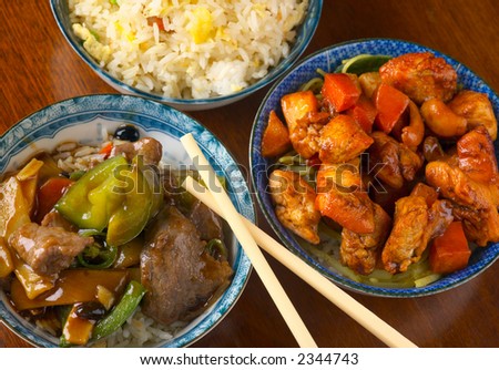 Delicious Chinese meal, with stir-fried beef in black bean sauce, chicken with cashew carrot in yellow bean sauce, rice, with chopsticks