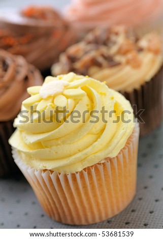 Cupcakes with a lemon cupcake at the front, shallow focus, focus on lemon buttercream.