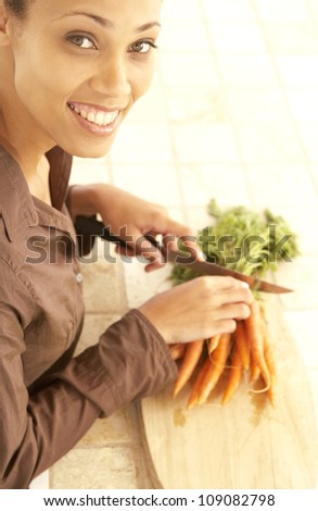 Beautiful African American woman with a lovely big smile preparing carrots in her kitchen