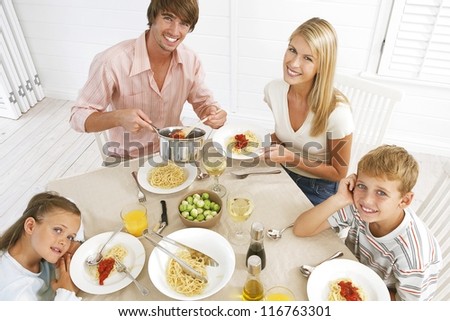 Overhead view of a young family sitting at the dining table eating spaghetti bolognaise