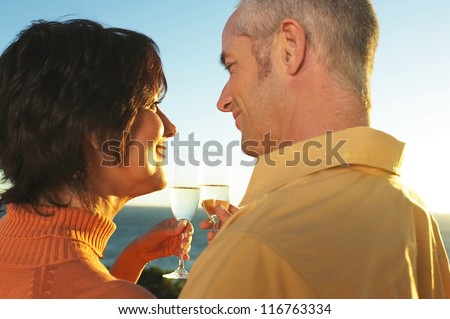 Loving couple standing in profile share a toast to each other and the setting sun