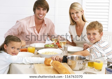 Young family seated at the table enjoying their meal of spaghetti bolognaise and salads