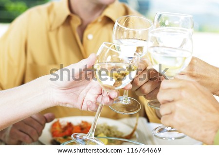 Cropped view image of four friends clinking their wine glasses and drinking a toast