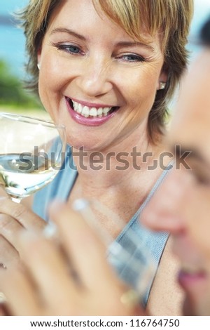 Beautiful woman smiling over a glass of wine as she sits at the dinner table socialising with her friends