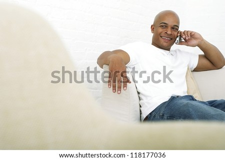 Handsome man sitting in white armchair and speaking on his mobile phone
