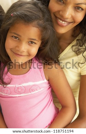 Lovely closeup portrait of a beautiful smiling young woman with her shy little daughter sitting on her lap