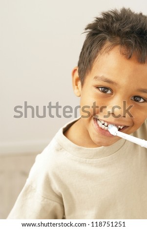 Young African American boy with a big smile brushing his teeth with a toothbrush