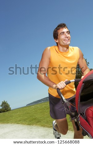 man jogging while pushing a stroller with blue sky overhead