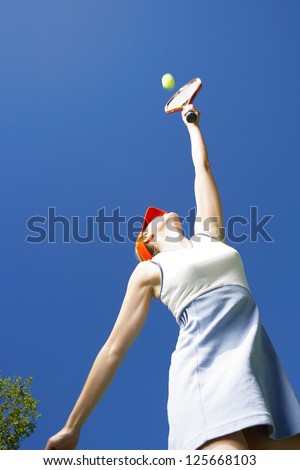 Low angle view of a woman stretching up to the ball with her racquet while serving