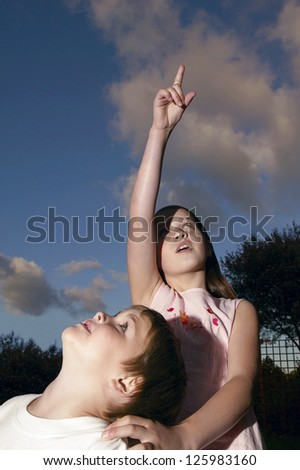 Young girl and her brother looking up into the heavens as she points out something of interest to him