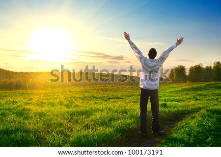 happy man with hands up on sunset background