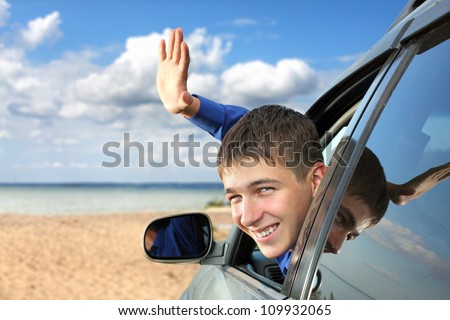 happy young man sitting in the car and wave goodbye
