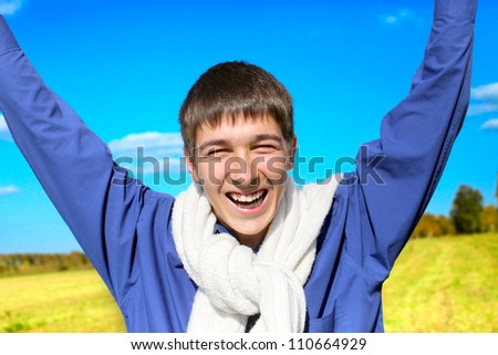 happy young man on autumn field rising up his hands