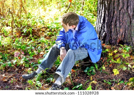 sad teenager sitting in the autumn forest