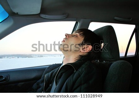young man sleeps in passenger compartment of the car