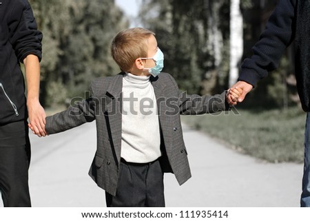 kid in the flu mask on the street with two persons