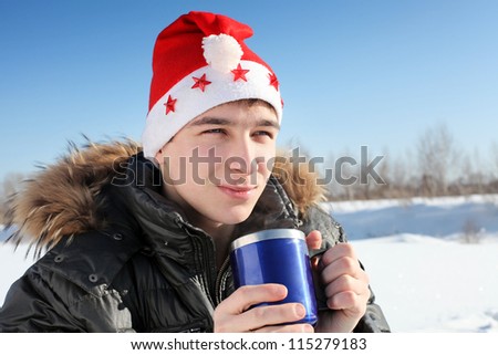 happy young man in santa\'s hat with travel mug in the winter