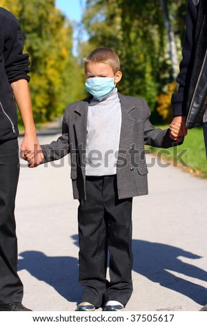 kid in the flu mask on the street with two persons