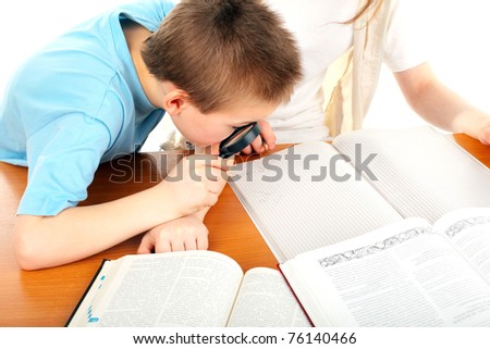 schoolboy with loupe on the table with exercise books