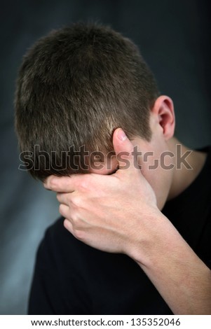 Sad Young Man On the Black Background hide his Face