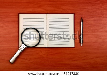 Writing Pad with Loupe and Pen on the Wooden Table