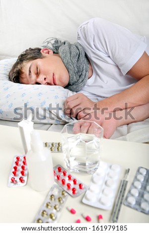 Sick Young Man sleeping on the Bed with Pills on foreground