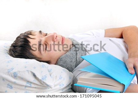 Tired Young Man Sleeps with a Book on the bed