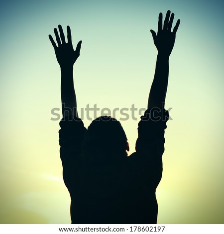 Toned photo of Silhouette of Praying Man on the Evening Sky Background
