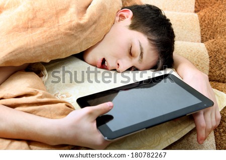 Tired Teenager sleeping on the Bed with Tablet Computer