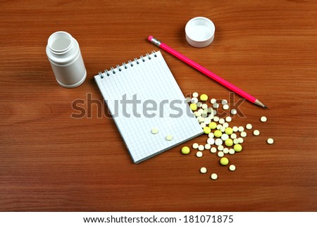Writing Pad and the Pills on the Wooden Table closeup