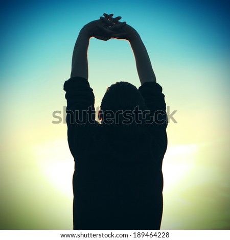 Toned photo of Man Silhouette with Hand up on Sunset Background