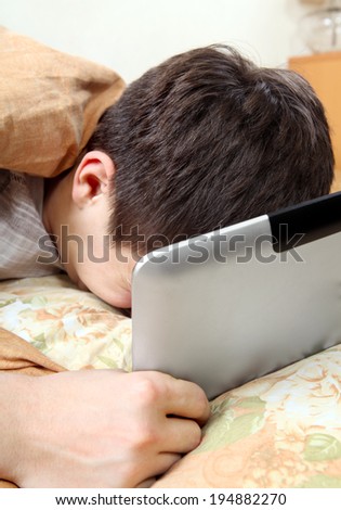 Sad Teenager Weeps with Tablet Computer in the Bed at the Home