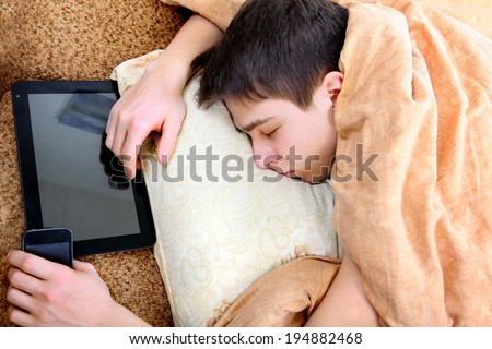 Tired Teenager sleeping at the Home with Tablet Computer