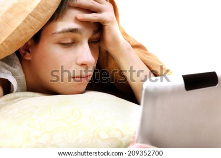 Serious Teenager with Tablet Computer under Blanket at the Home