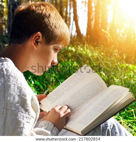 Teenage Boy sit in the Forest with a Book